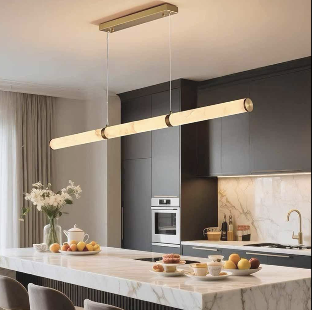 Linear illuminated pendant suspended above a pale marble kitchen island