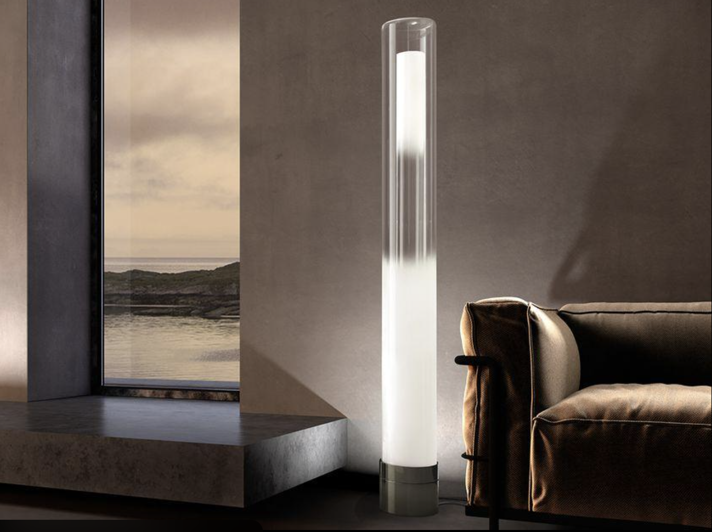Tall glass floor light beside a dark armchair overlooking the coast