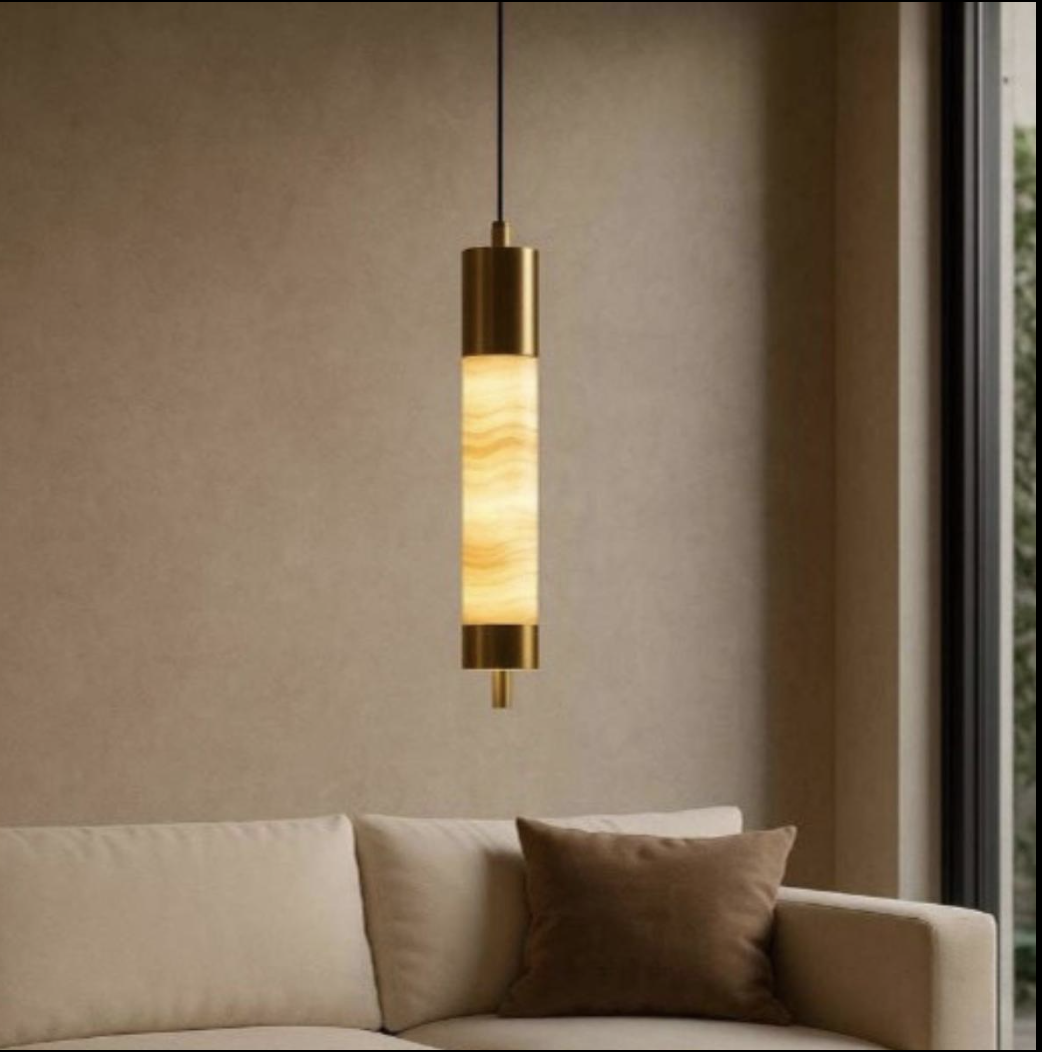 Slender illuminated stone pendant beside a neutral sofa